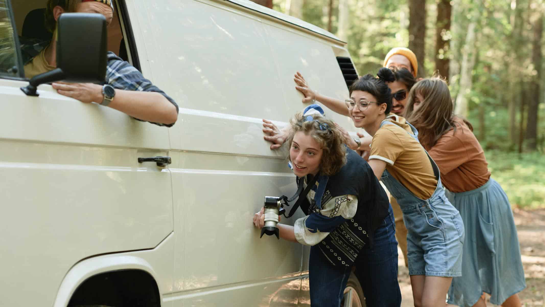 Junge Menschen schieben einen VW-Bus an